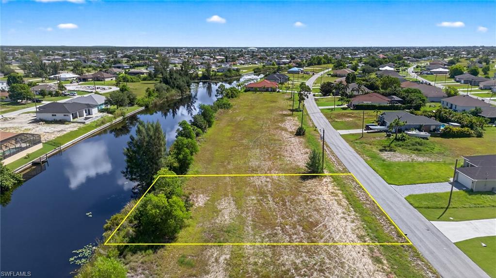 Aerial view of residential area with property boundaries highlighted and a nearby body of water