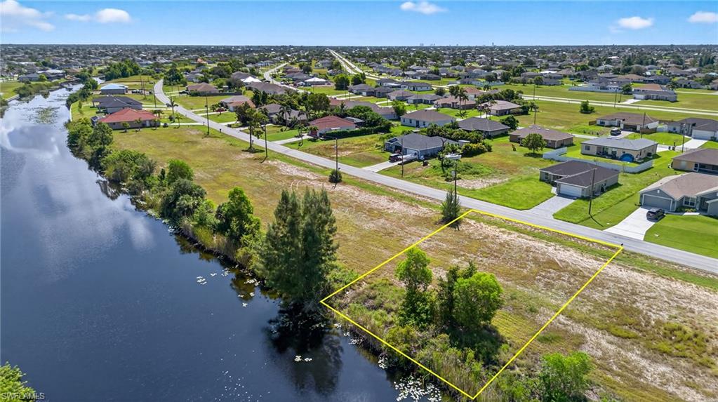 Aerial view of residential area featuring a nearby body of water and property boundaries highlighted