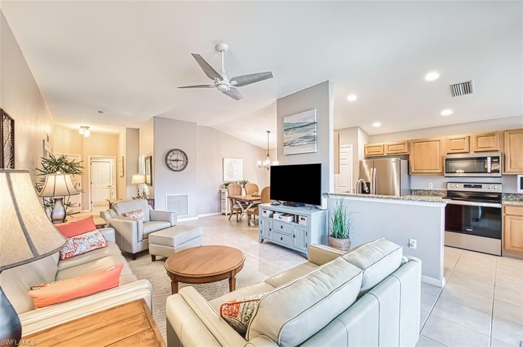 Living room with light tile patterned floors, lofted ceiling, a ceiling fan, a chandelier, and recessed lighting