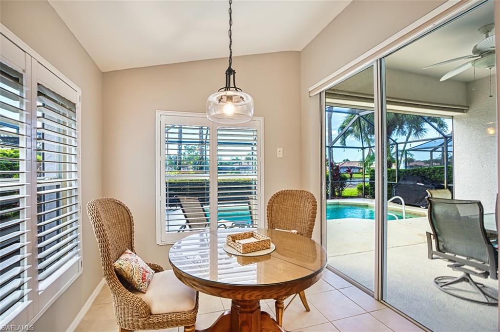 Tiled dining room with a sunroom, ceiling fan, plenty of natural light, and vaulted ceiling