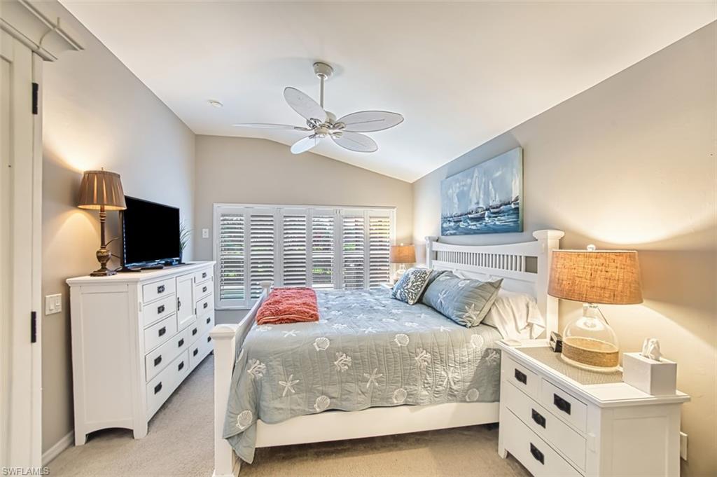 Bedroom with light colored carpet, vaulted ceiling, and a ceiling fan