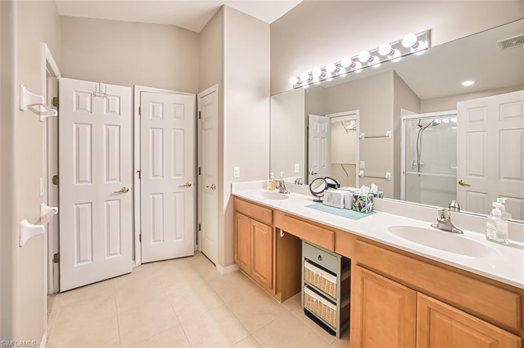 Full bath with a stall shower, a closet, light tile patterned flooring, and double vanity