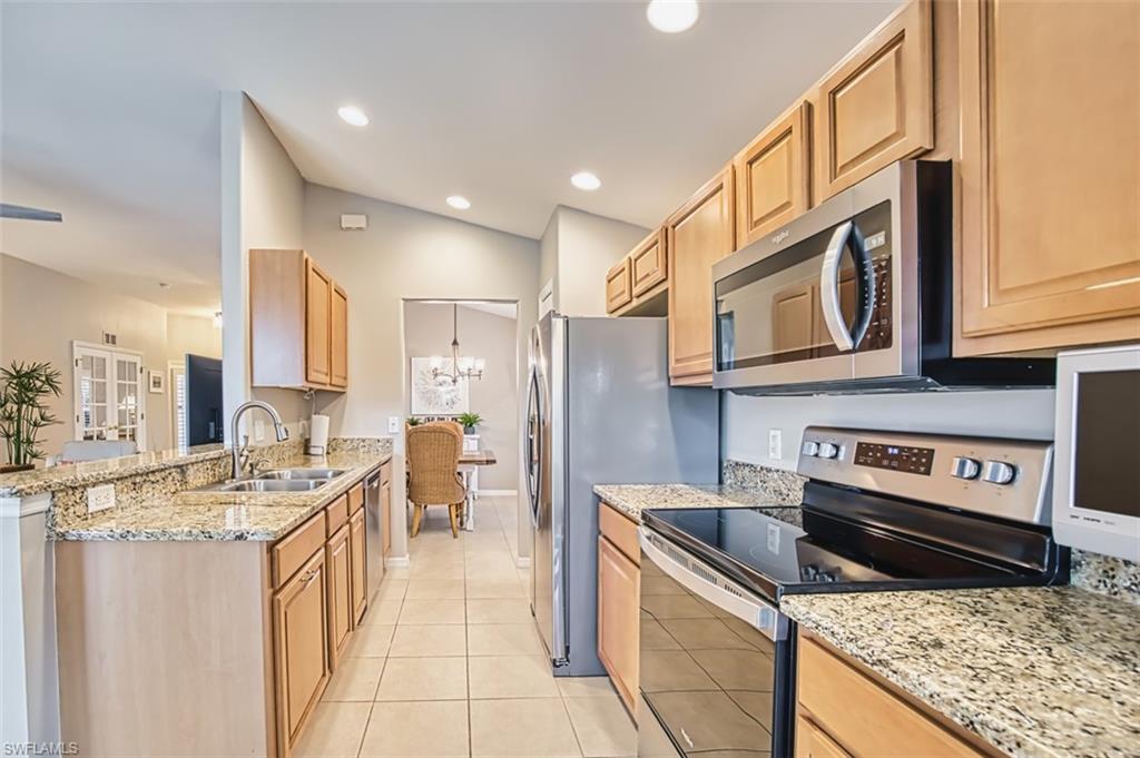 Kitchen with appliances with stainless steel finishes, light stone countertops, a chandelier, light tile patterned floors, and recessed lighting