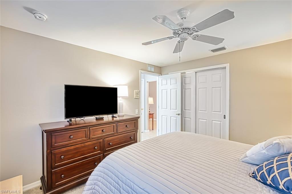 Bedroom with light carpet, a ceiling fan, and a closet