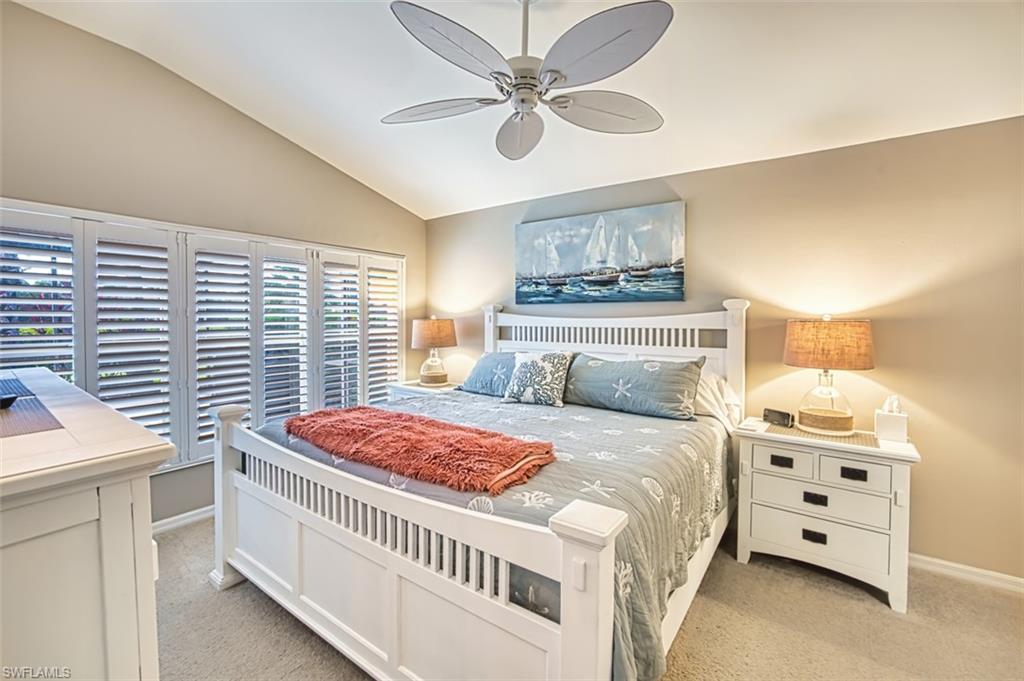 Bedroom featuring light carpet, vaulted ceiling, and a ceiling fan