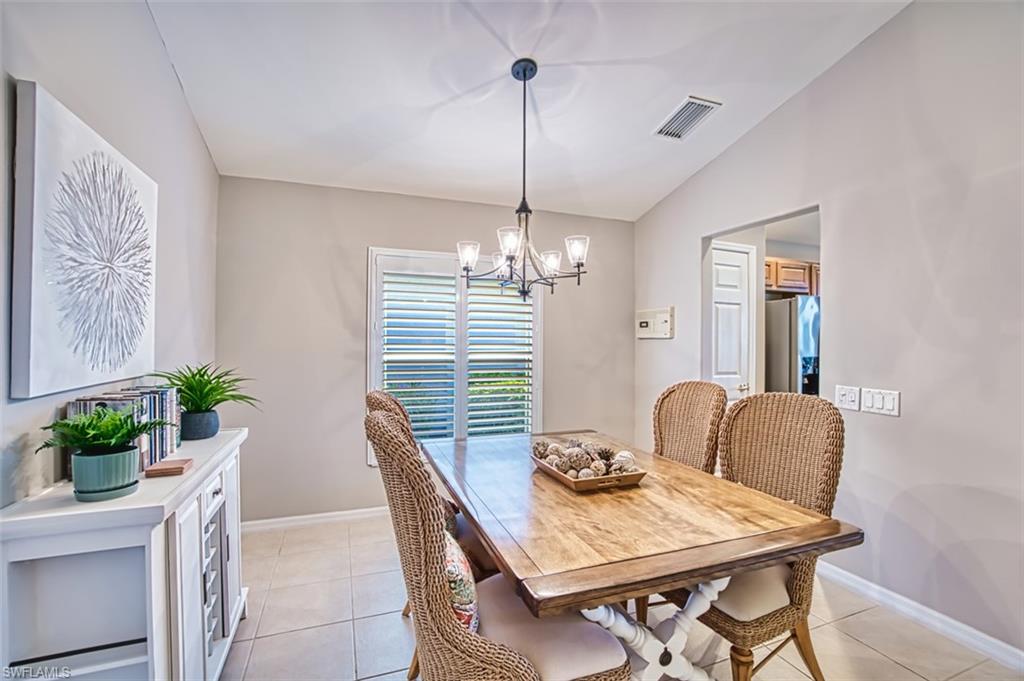 Dining space with light tile patterned floors, vaulted ceiling, and a chandelier