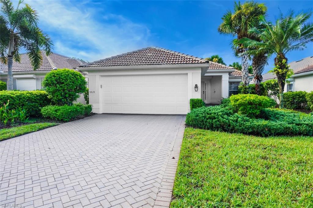 View of front of home featuring decorative driveway, stucco siding, a garage, a tile roof, and a front lawn