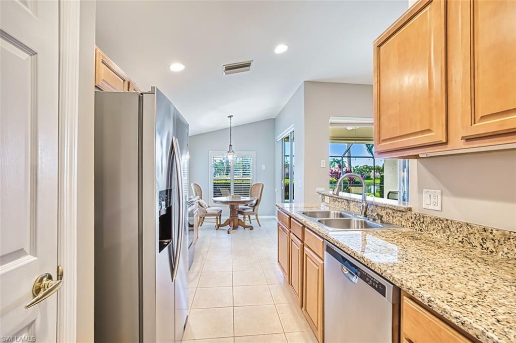 Kitchen with stainless steel appliances, pendant lighting, light tile patterned flooring, light stone countertops, and recessed lighting