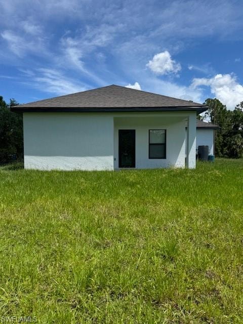 Rear view of property with stucco siding and a lawn