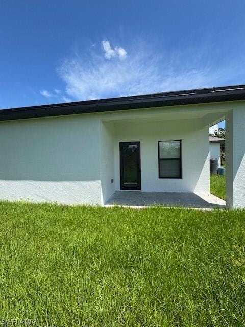 Back of house featuring stucco siding, a yard, and a patio