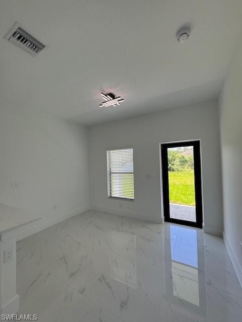 Unfurnished room with light marble finish flooring and baseboards, rear exit door.