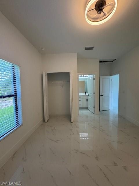 Unfurnished bedroom with a closet, light marble finish flooring, and connected bathroom