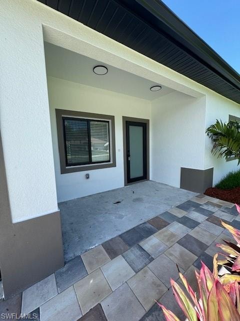Entrance to property with stucco siding and a patio area
