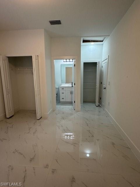 Primary bedroom with bathroom enclose  featuring vanity, 2 closet, and light marble finish floors.