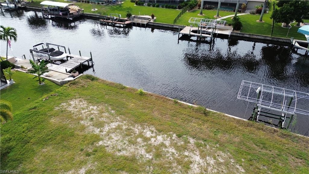 Dock area with a water view, boat lift, and a lawn