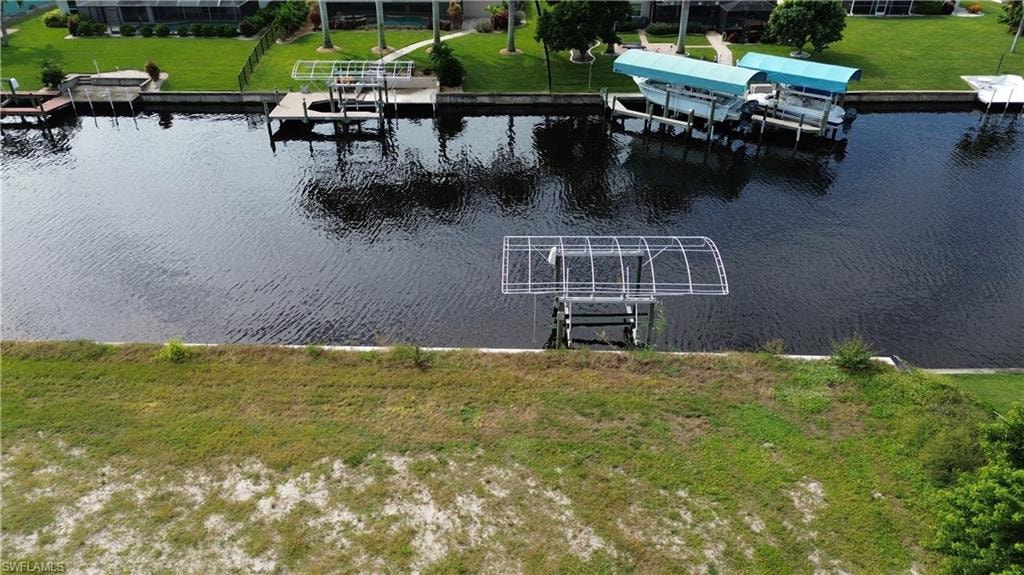 Dock with boat lift, a water view, and a lawn