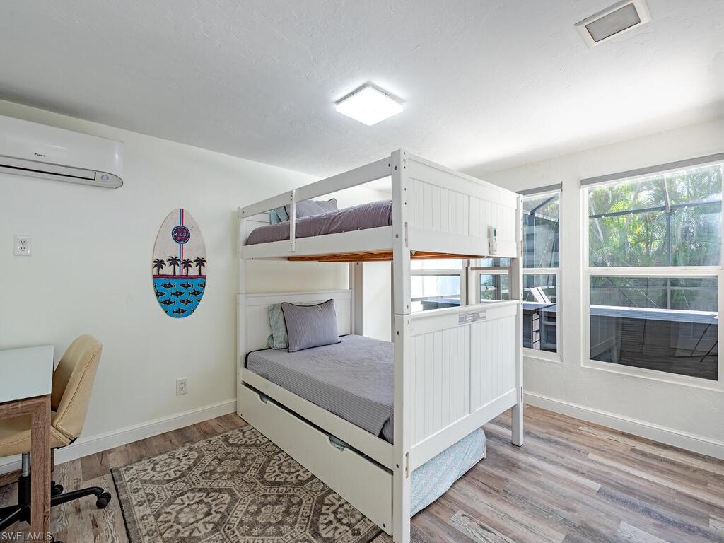 Bedroom featuring light wood-style floors, a wall mounted air conditioner, and a desk