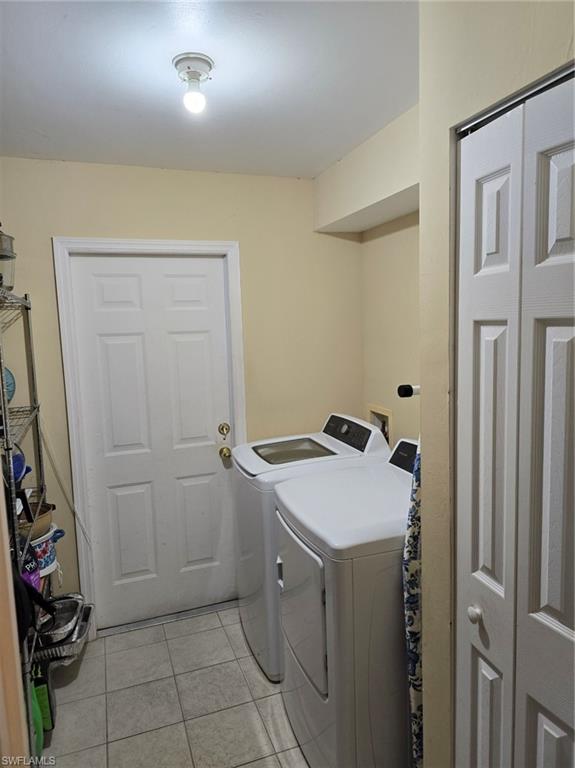 Washroom with light tile patterned floors and washer and dryer