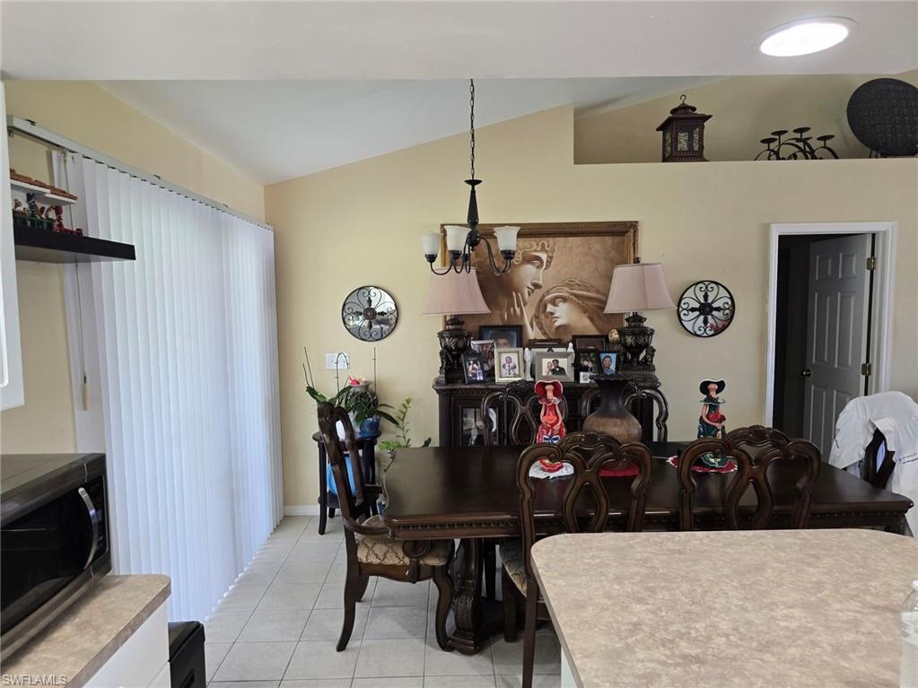 Dining room featuring vaulted ceiling, light tile patterned flooring, and a chandelier