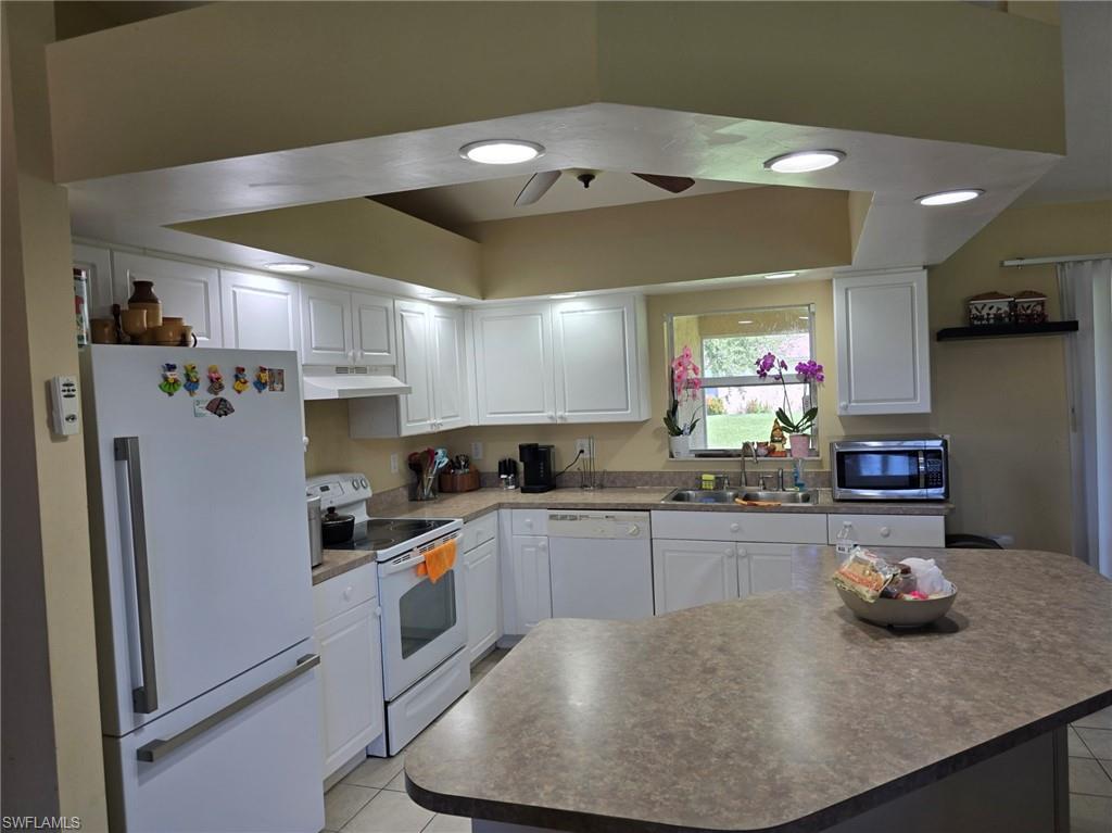 Kitchen with white appliances, white cabinetry, light tile patterned floors, and recessed lighting