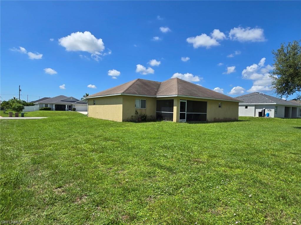 Back of house with a sunroom, stucco siding, and a yard