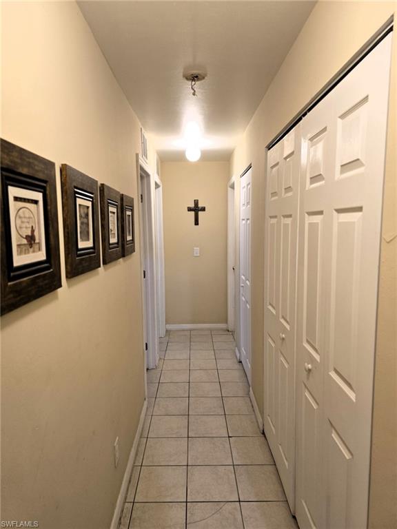 Hallway featuring light tile patterned floors and baseboards