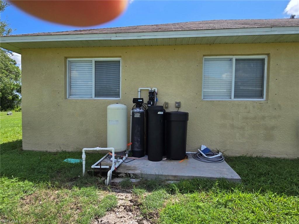 Exterior view of stucco siding, a water softener system, and a water pressure tank