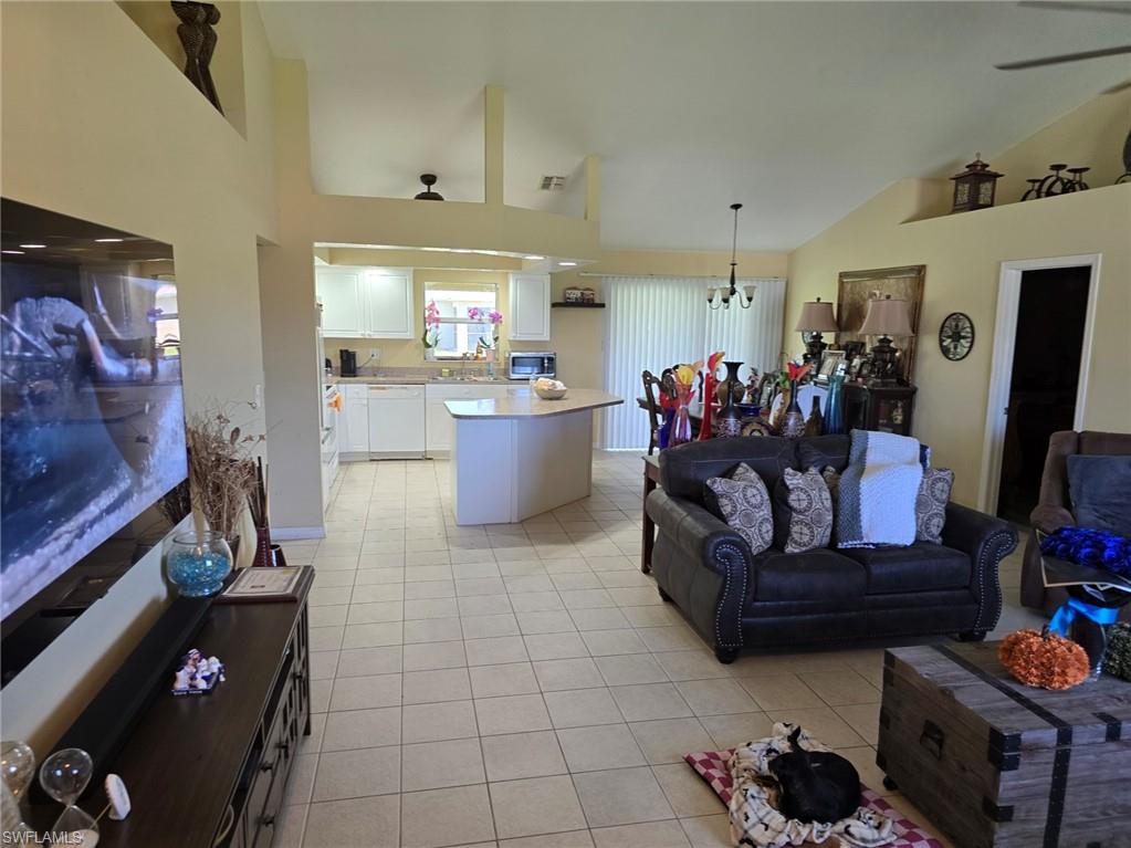 Living area featuring high vaulted ceiling, light tile patterned flooring, and a chandelier