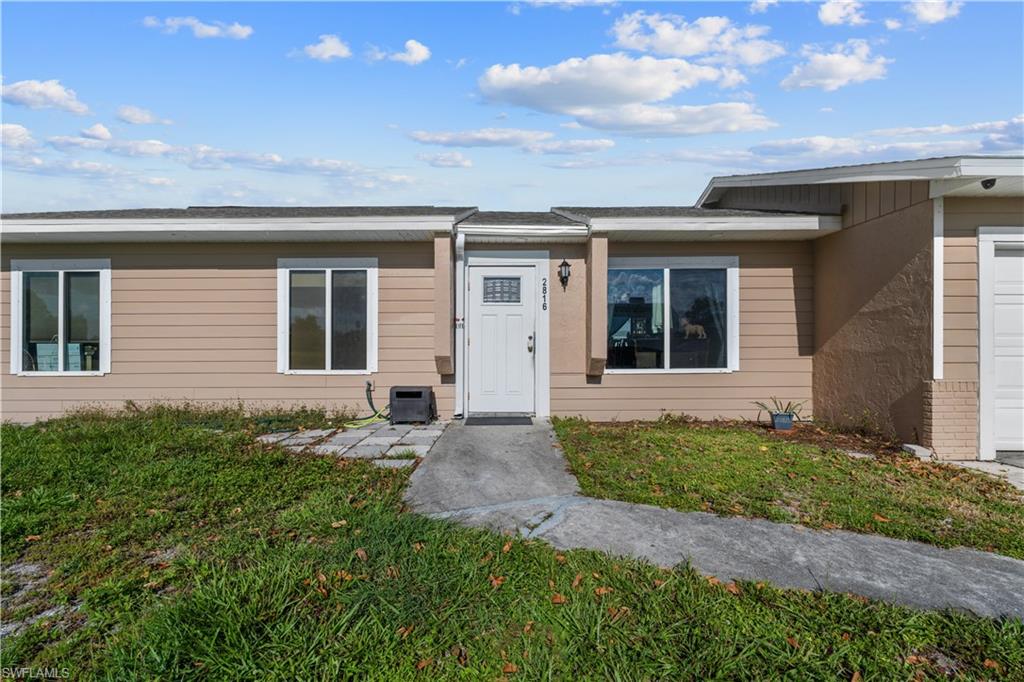 Entrance to property with an attached garage and a lawn