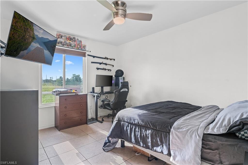Tiled bedroom with a desk and ceiling fan