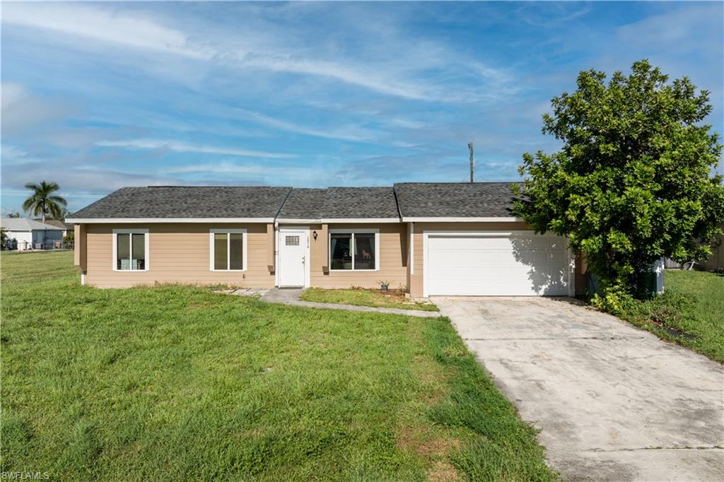 Ranch-style house with an attached garage, a front yard, driveway, and a shingled roof