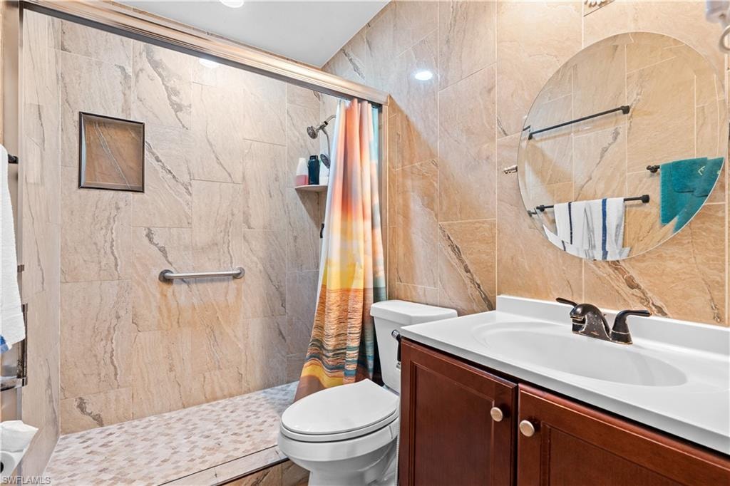 Bathroom with tile walls, vanity, and a shower stall