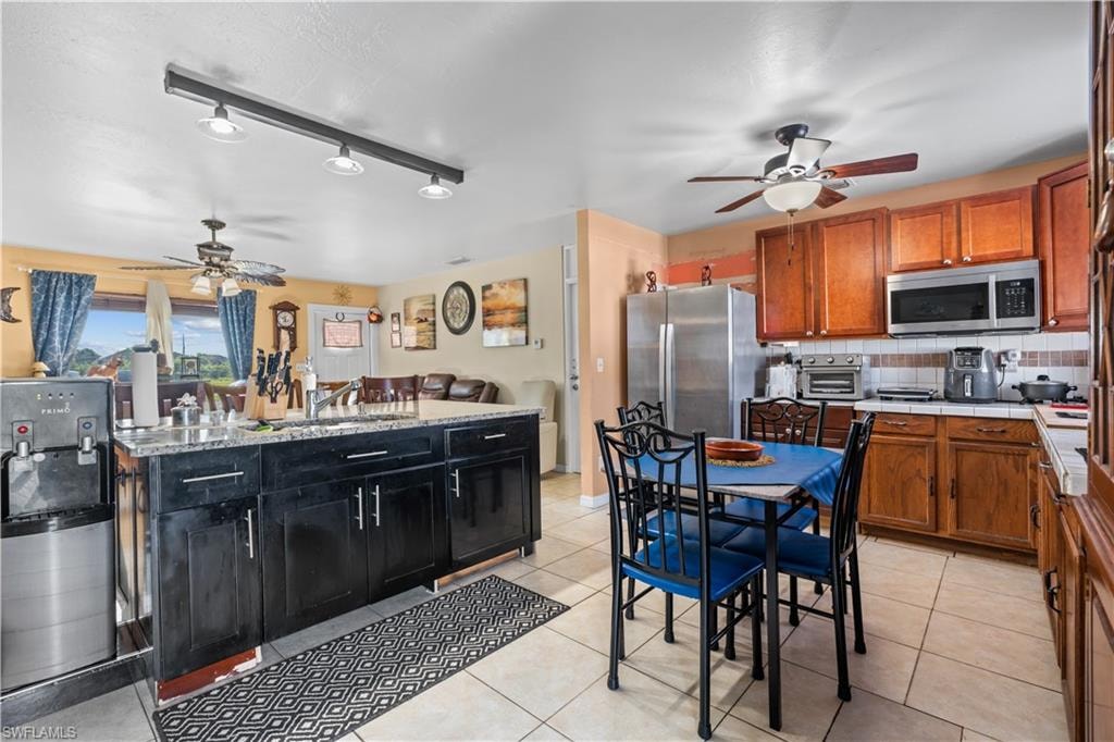 Kitchen featuring ceiling fan, tasteful backsplash, rail lighting, and light tile patterned flooring