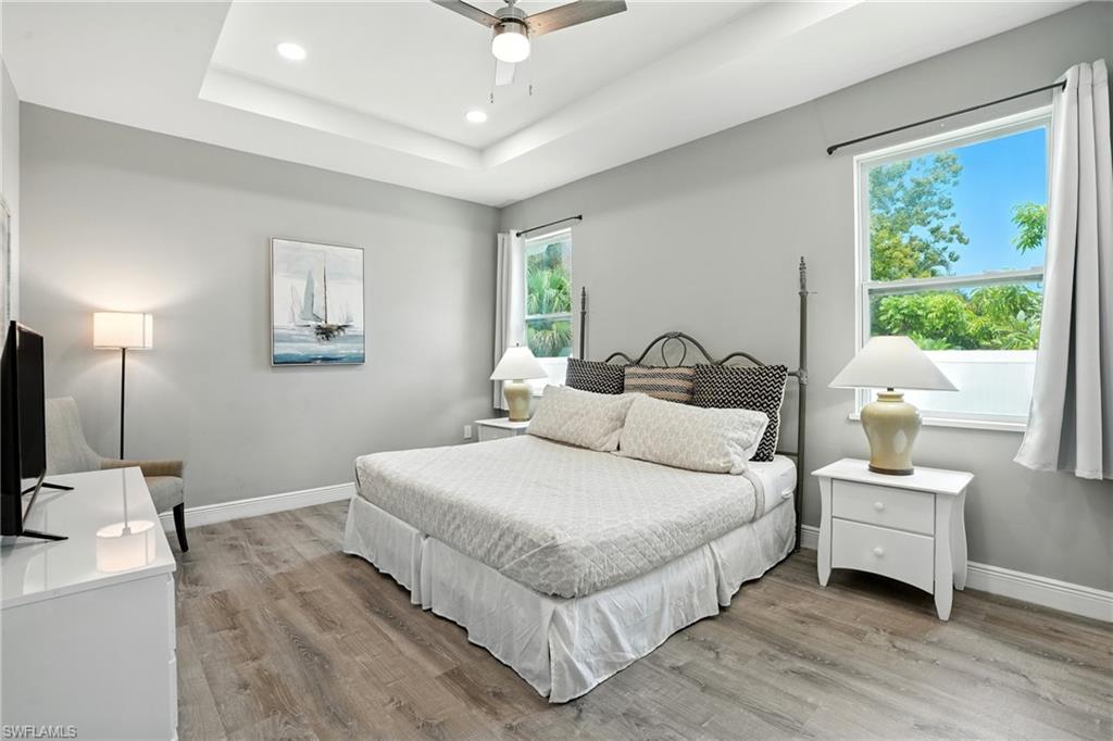 Bedroom featuring light wood finished floors, ceiling fan, recessed lighting, and a raised ceiling