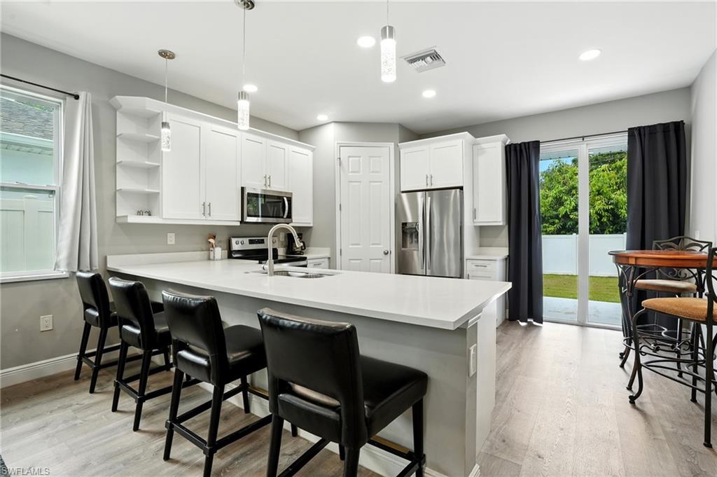 Kitchen with appliances with stainless steel finishes, open shelves, white cabinetry, light wood-style floors, and recessed lighting