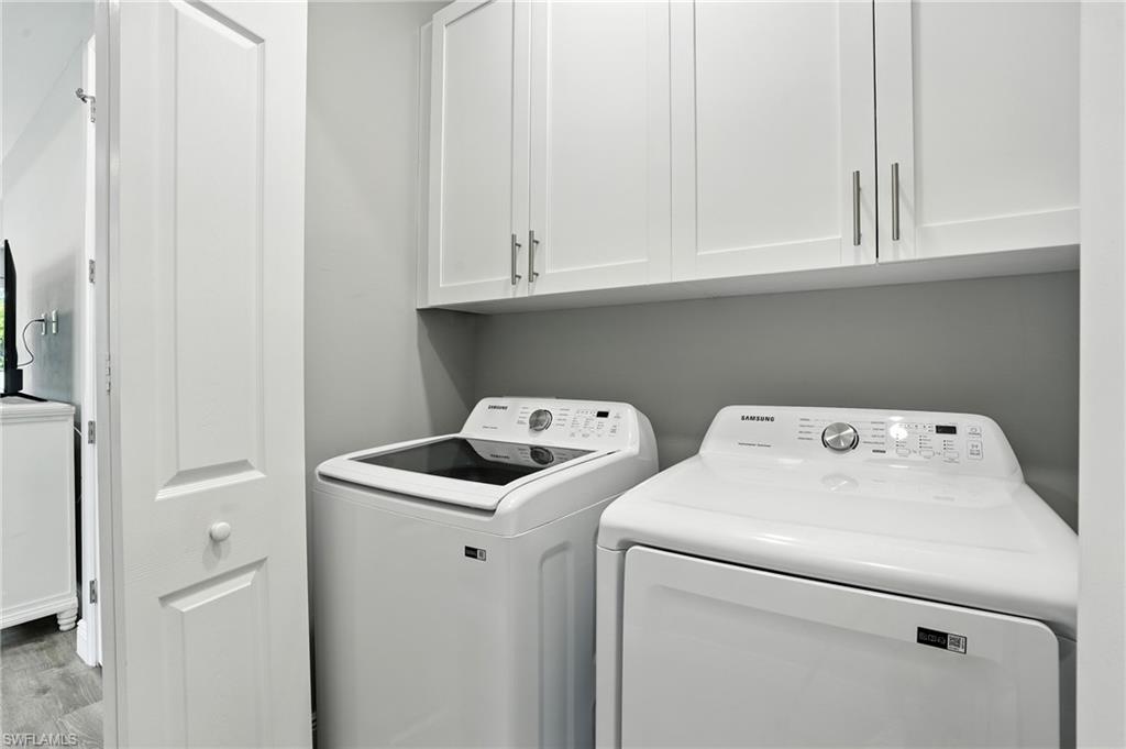Laundry area with washing machine and clothes dryer, cabinet space, and wood finished floors