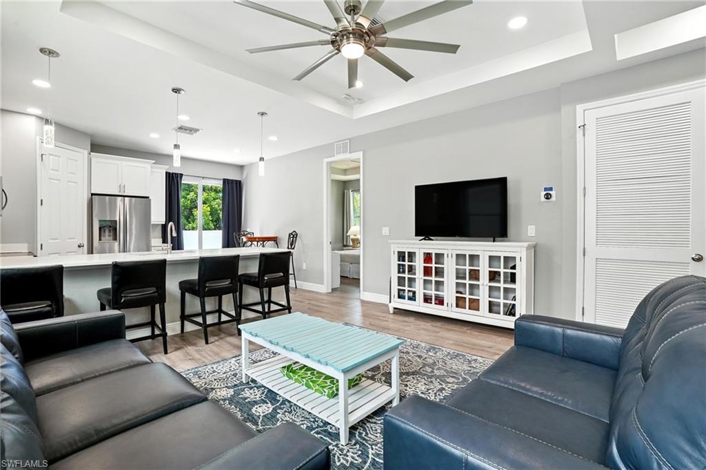 Living area featuring a tray ceiling, recessed lighting, light wood-style flooring, and a ceiling fan