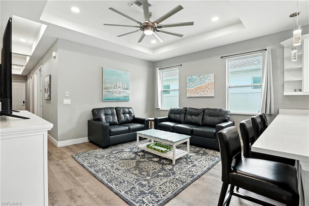 Living area featuring a tray ceiling, light wood finished floors, a ceiling fan, and recessed lighting