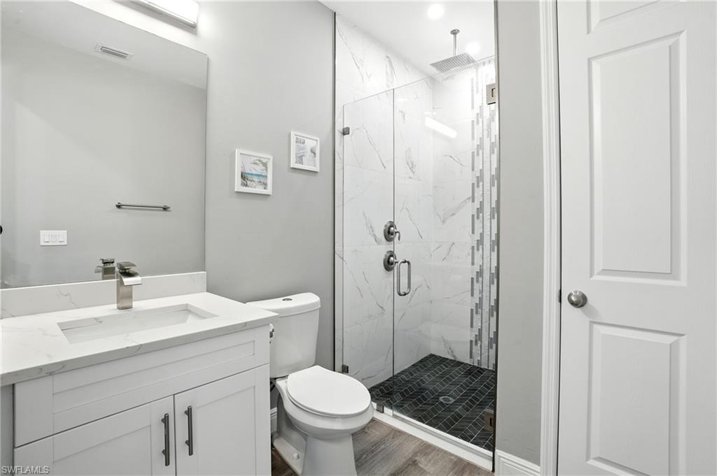 Bathroom featuring a marble finish shower, vanity, and wood finished floors