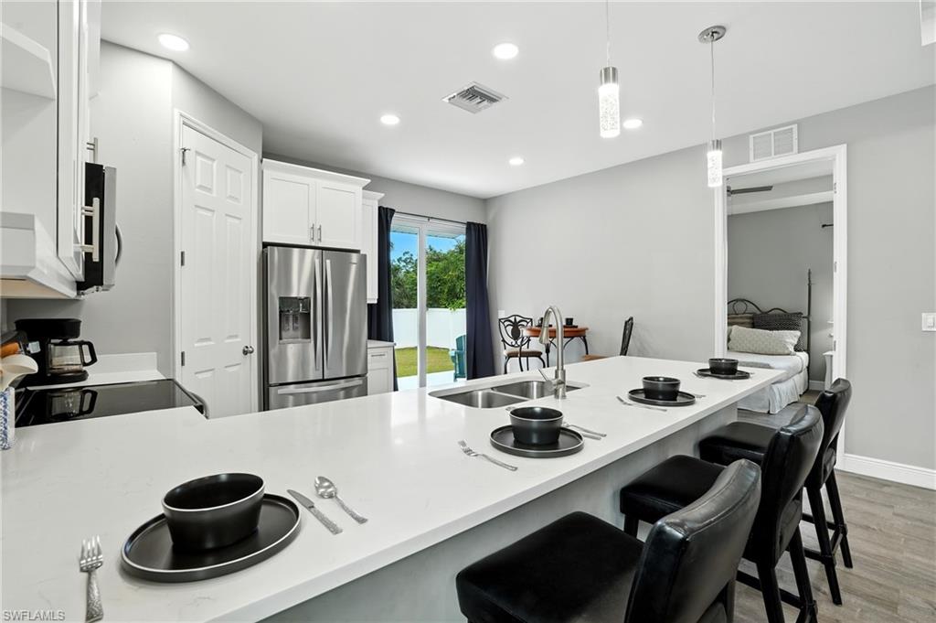 Kitchen featuring a peninsula, a breakfast bar, appliances with stainless steel finishes, light wood finished floors, and recessed lighting