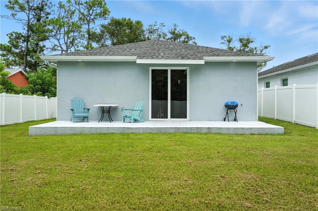 Rear view of house with a patio, roof with shingles, and stucco siding