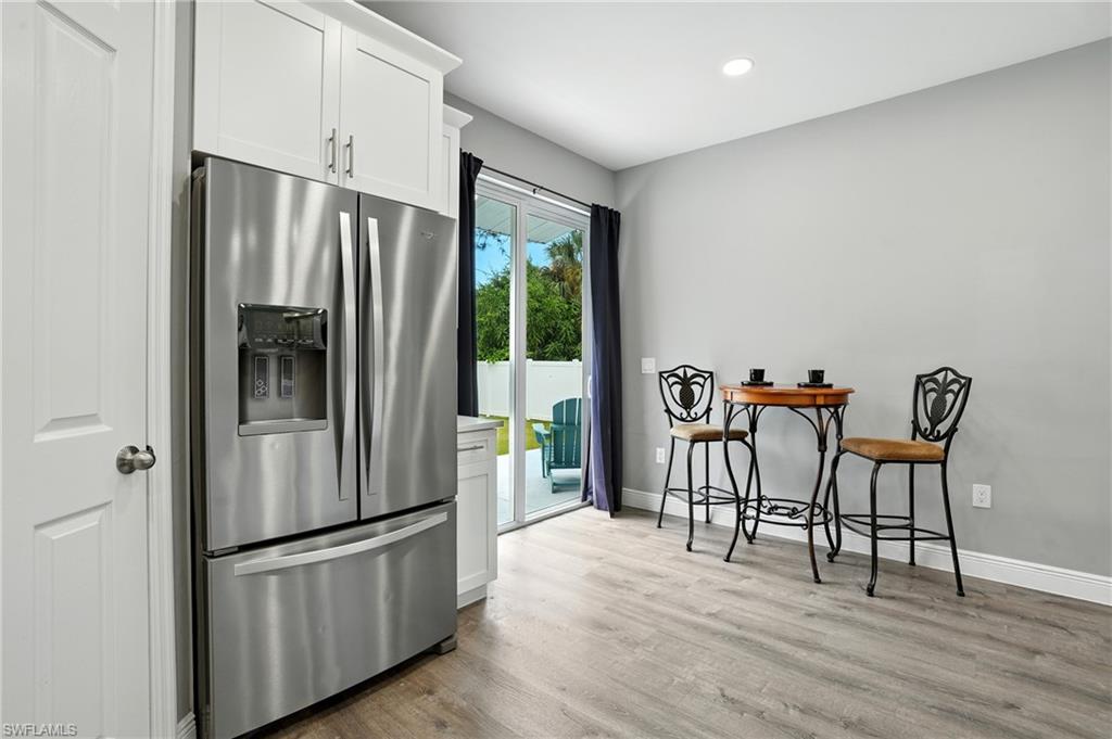 Kitchen with stainless steel refrigerator with ice dispenser, white cabinetry, light wood-style flooring, recessed lighting, and light countertops
