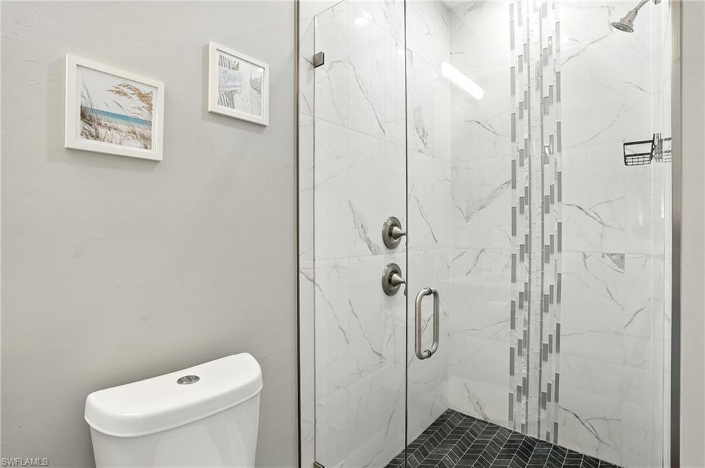 Bathroom with a marble finish shower and toilet