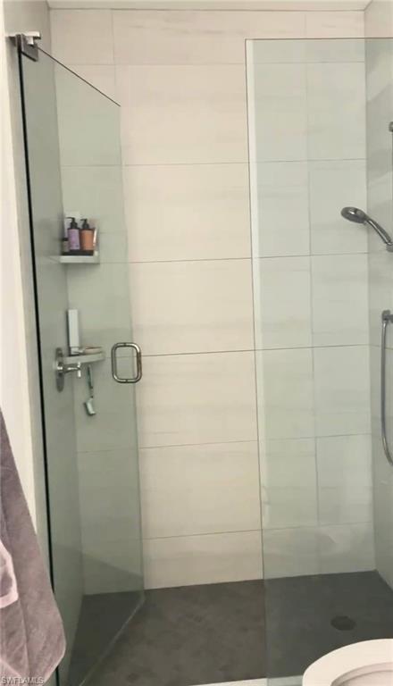 Full bath featuring a shower stall and toilet