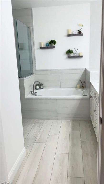 Full bathroom with vanity, a garden tub, and a shower stall