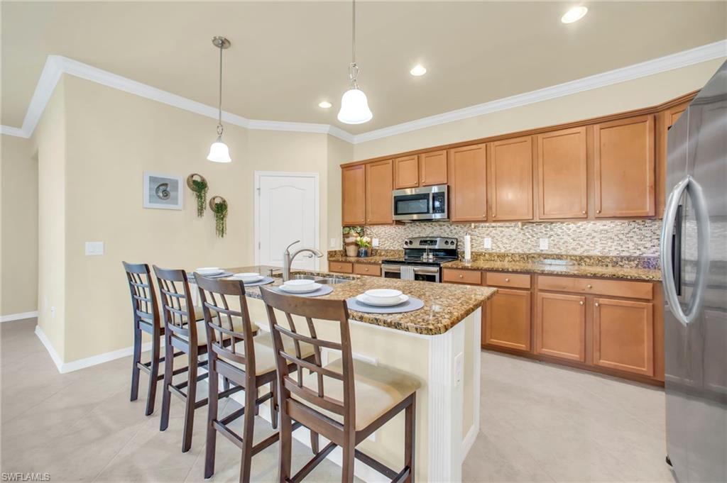 Kitchen with stone countertops, tasteful backsplash, crown molding, a breakfast bar area, and walk in pantry