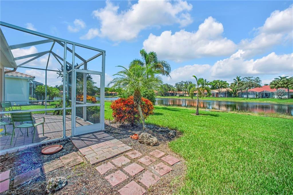 View of green lawn with a patio area, a lanai, a water view, and a sunroom