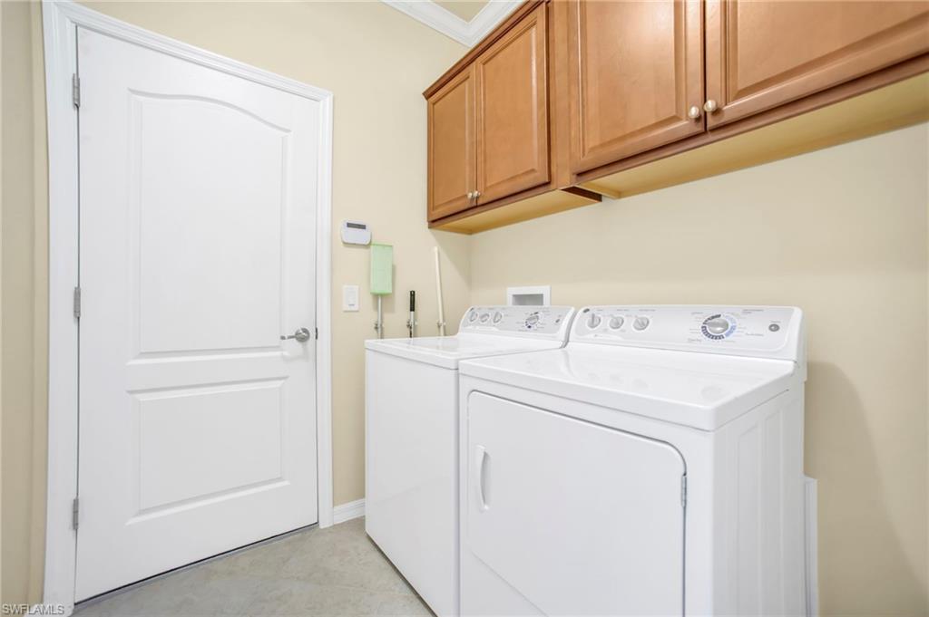 Laundry room featuring cabinet space, washer and dryer, and crown molding