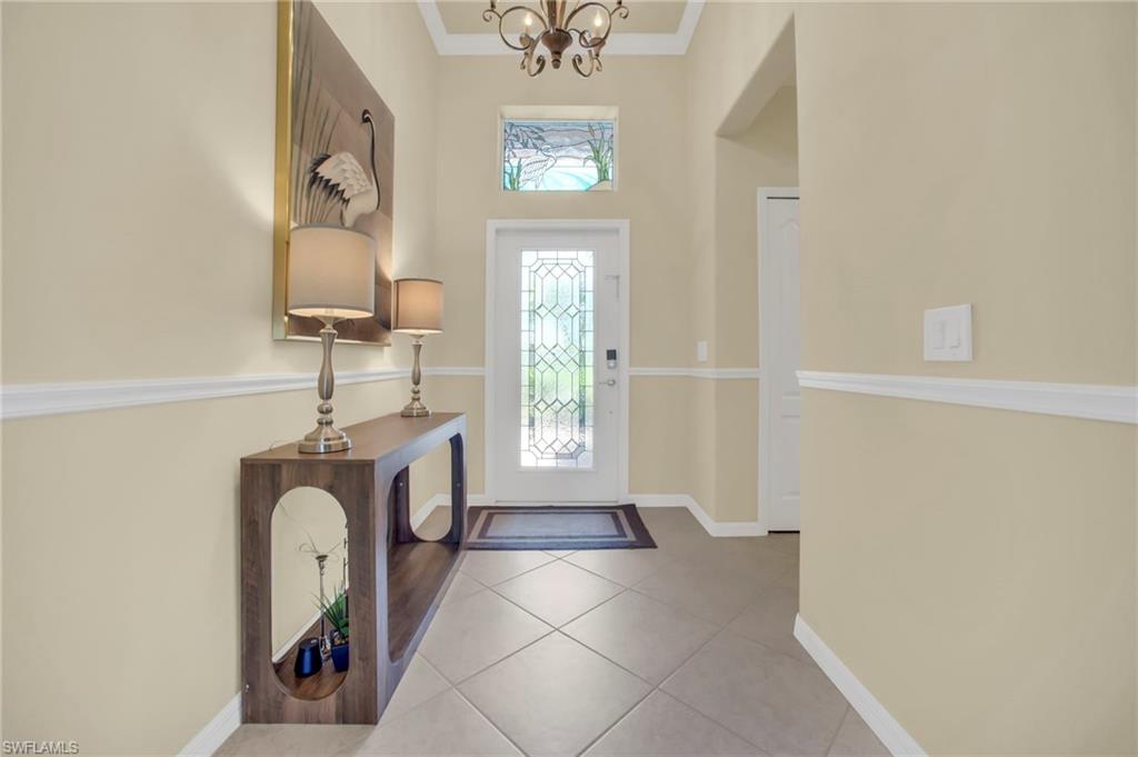 Tiled entryway featuring crown molding, a chandelier and beautiful stain glass