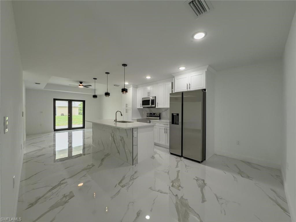 Kitchen featuring appliances with stainless steel finishes, recessed lighting, open floor plan, white cabinetry, and light marble finish flooring